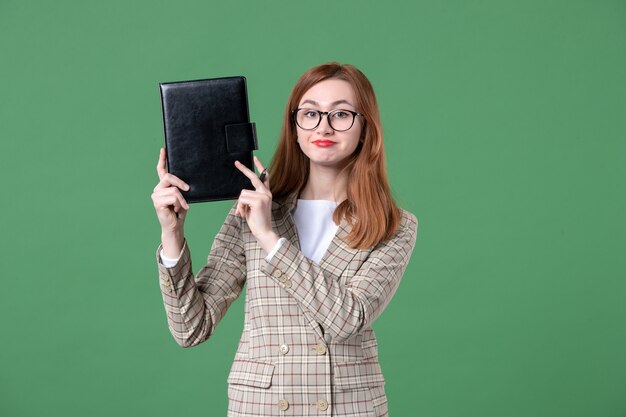 Retrato de maestra sosteniendo el bloc de notas en verde