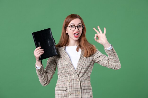 Retrato de maestra sosteniendo el bloc de notas en verde