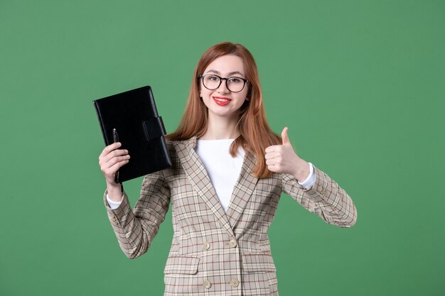 Retrato de maestra sosteniendo el bloc de notas en verde