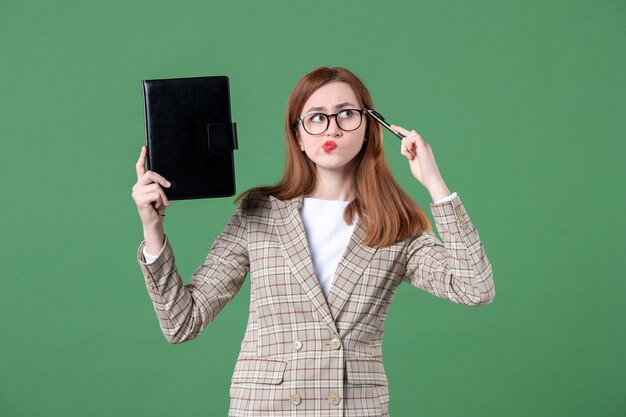 Retrato de maestra sosteniendo el bloc de notas en verde