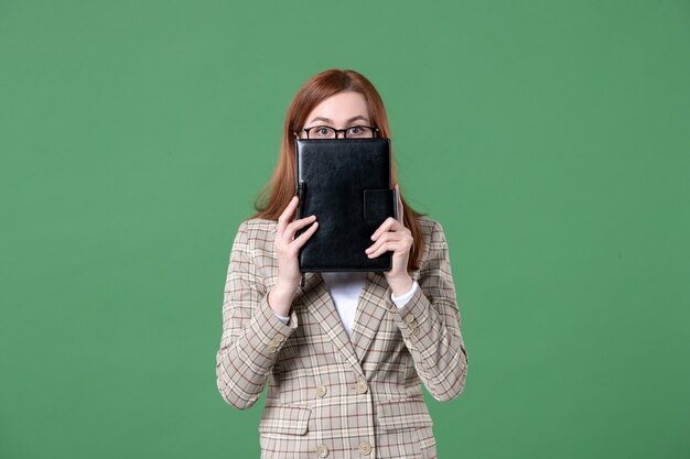 Retrato de maestra sosteniendo el bloc de notas en verde