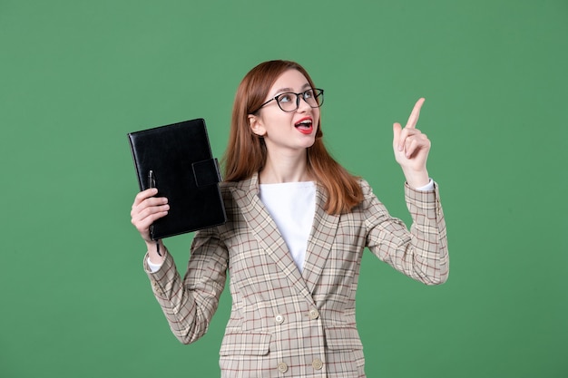 Retrato de maestra sosteniendo el bloc de notas en verde