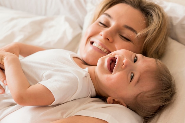 Foto gratuita retrato de mamá y bebé sentado en la cama