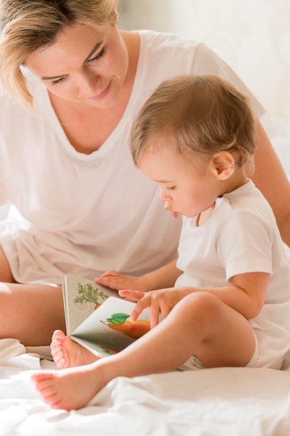 Retrato de mamá leyendo al bebé en la cama