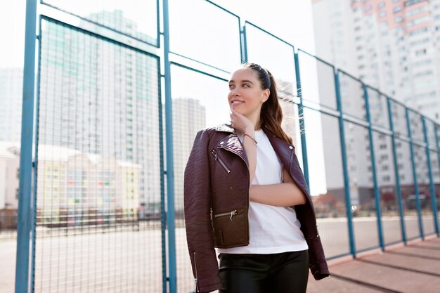 Retrato de maravillosa modelo blanca con maquillaje brillante que expresa energía en buenos días en la metrópoli