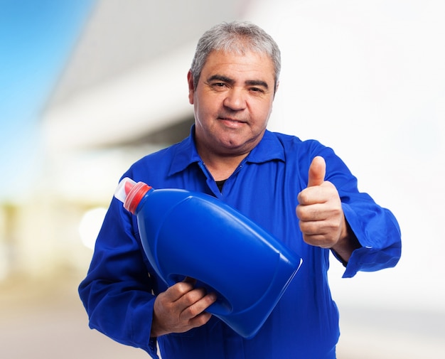 Foto gratuita retrato de un mecánico sosteniendo una botella de aceite