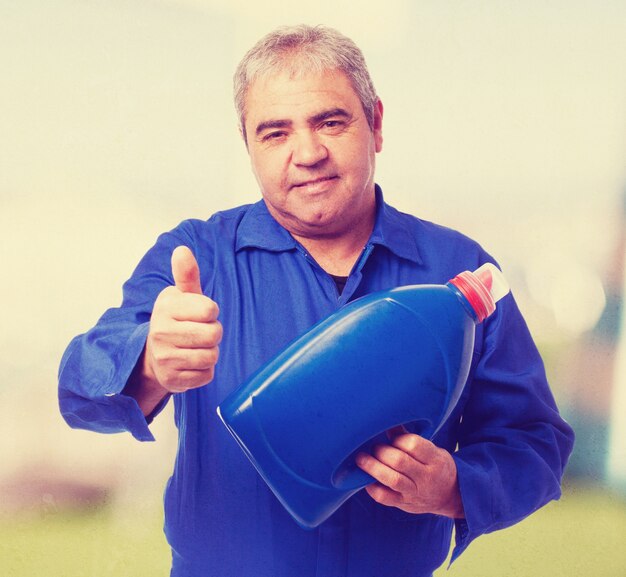 retrato de un mecánico sosteniendo una botella de aceite