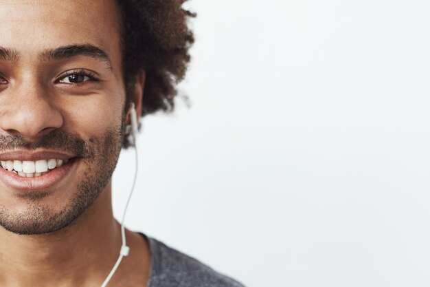 Retrato de media cara de hombre feliz africn en auriculares sonriendo.