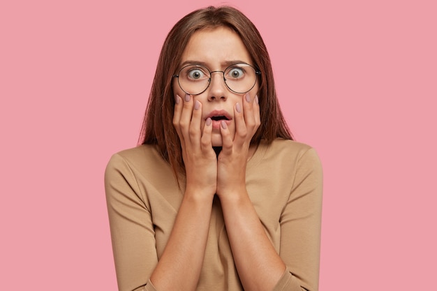 Retrato de media longitud de hermosa mujer muy emocional y sorprendida, mira fijamente con ojos saltones, tiene estupor