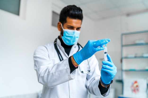 Retrato de un médico indio que se prepara para vacunar a un paciente.