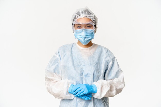 Retrato de médico o enfermera asiática en equipo de protección personal ppe de pie en p ...