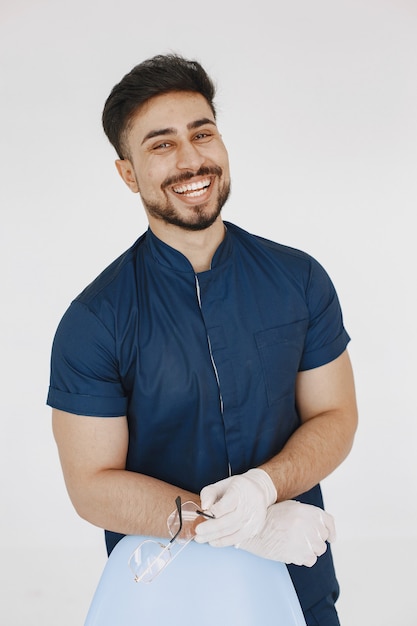 Un retrato de un médico posando contra la pared blanca