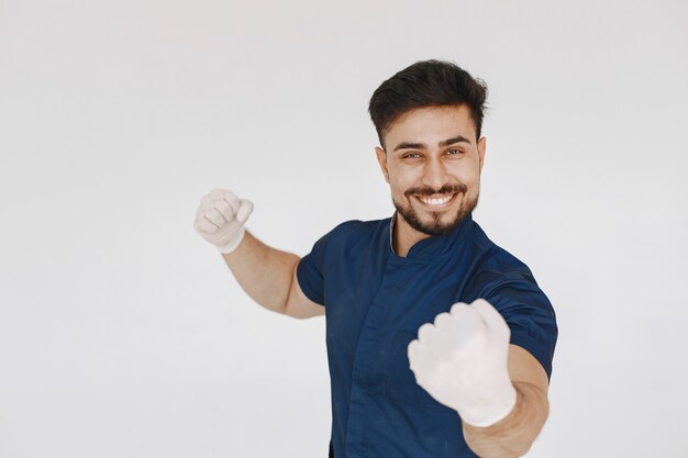 Un retrato de un médico posando contra la pared blanca