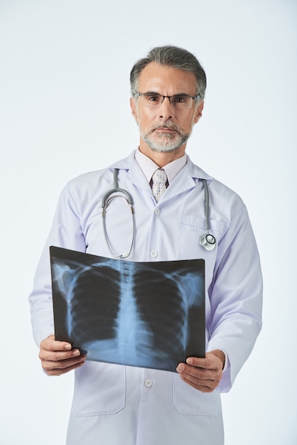 Retrato de médico profesional sosteniendo la radiografía de tórax y mirando a la cámara