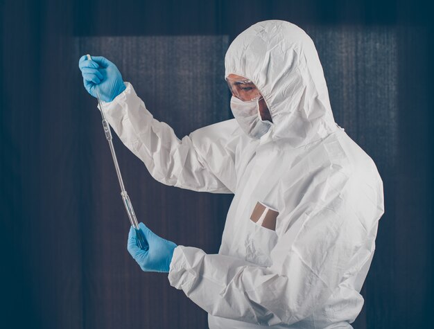 Retrato de un médico tomando muestras de medicamentos con máscara, guantes y traje protector