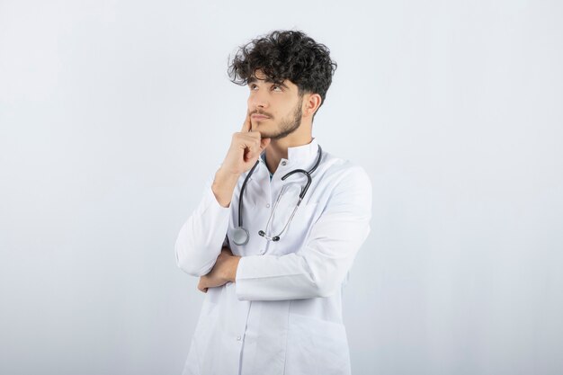 Retrato de un médico varón seguro mirando hacia arriba aislado en blanco.