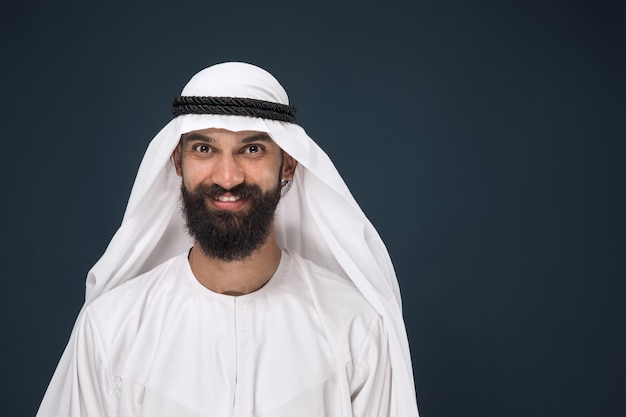 Foto gratuita retrato de medio cuerpo del empresario saudí árabe en la pared azul oscuro del estudio