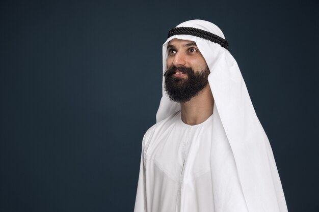 Retrato de medio cuerpo del empresario saudí árabe en la pared azul oscuro del estudio