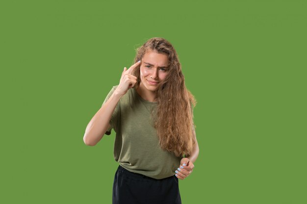 Retrato de medio cuerpo femenino hermoso aislado en estudio verde. La joven mujer sorprendida emocional