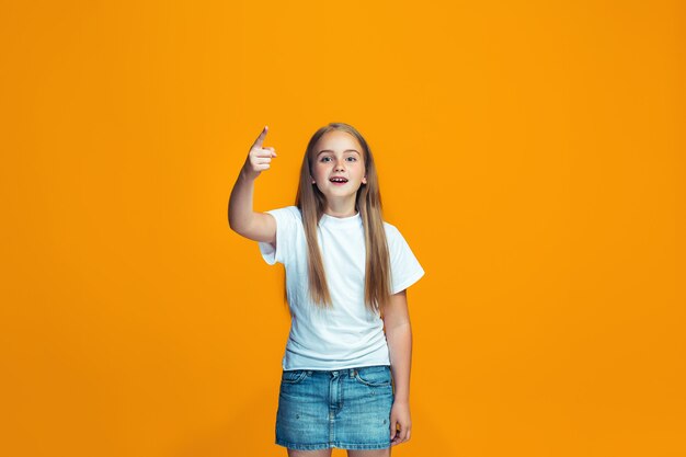 Retrato de medio cuerpo femenino hermoso en fondo anaranjado del estudio. La joven adolescente emocional