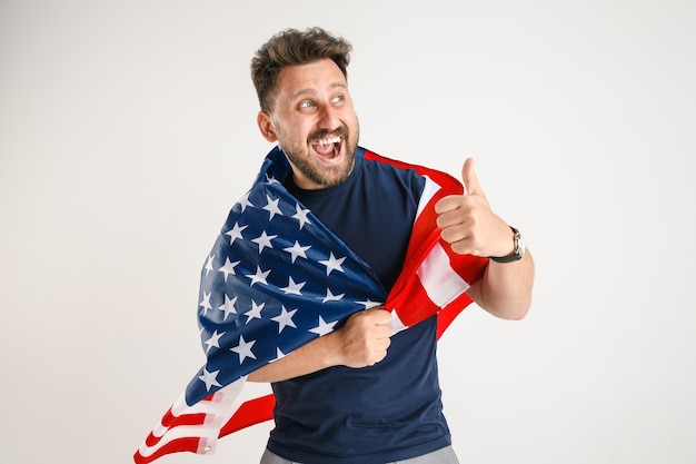 Foto gratuita retrato de medio cuerpo de un joven con la bandera de los estados unidos aislado en el estudio blanco.