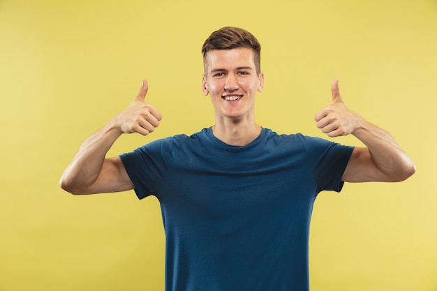 Retrato de medio cuerpo del joven caucásico en el espacio amarillo. Hermoso modelo masculino en camisa azul