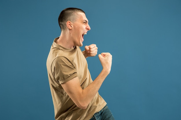 Retrato de medio cuerpo del joven caucásico en el espacio azul. Hermoso modelo masculino en camisa