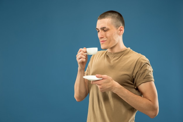 Retrato de medio cuerpo del joven caucásico en el espacio azul. Hermoso modelo masculino en camisa