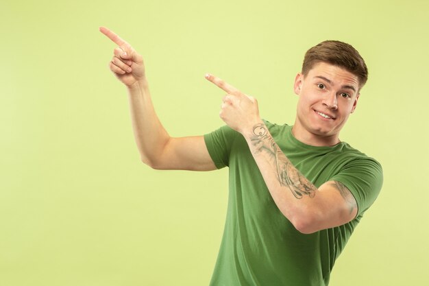 Retrato de medio cuerpo del joven caucásico en el espacio verde del estudio. Hermoso modelo masculino en camisa