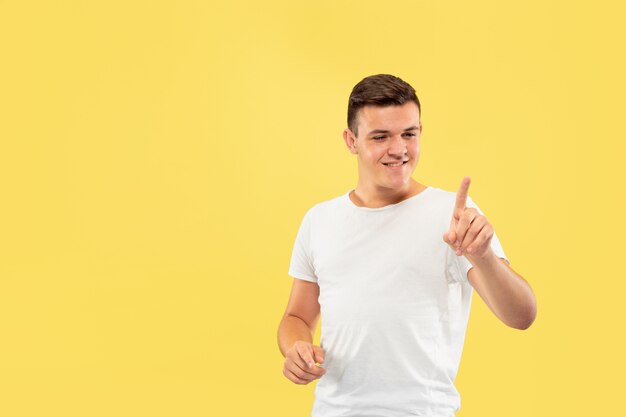 Retrato de medio cuerpo del joven caucásico en estudio amarillo