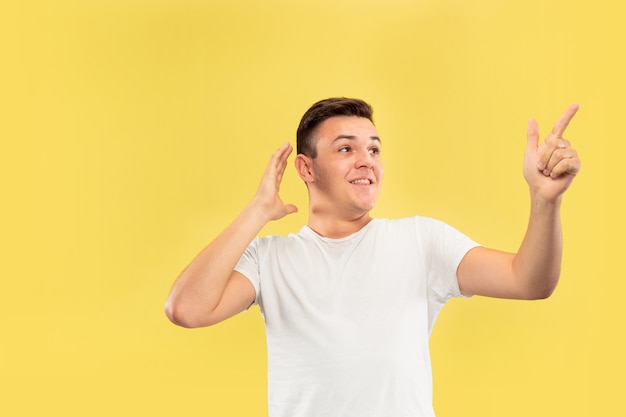 Retrato de medio cuerpo del joven caucásico en estudio amarillo