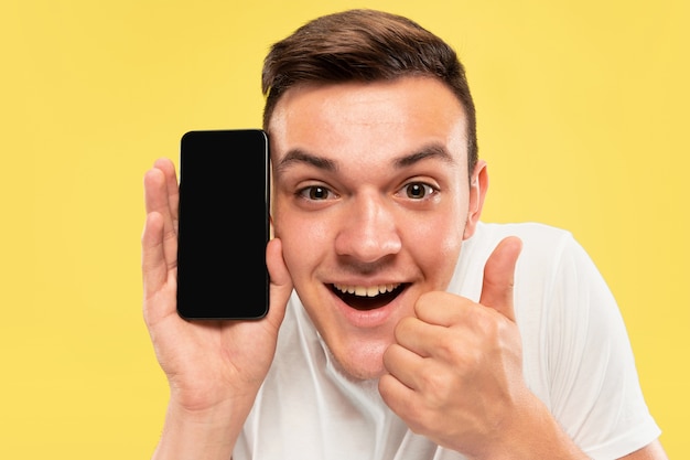 Retrato de medio cuerpo del joven caucásico en estudio amarillo