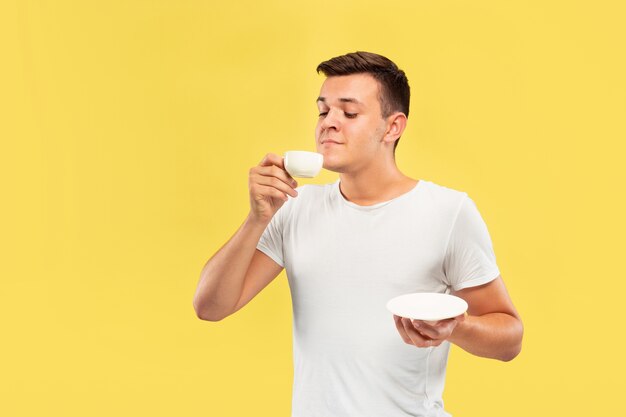 Retrato de medio cuerpo del joven caucásico en estudio amarillo