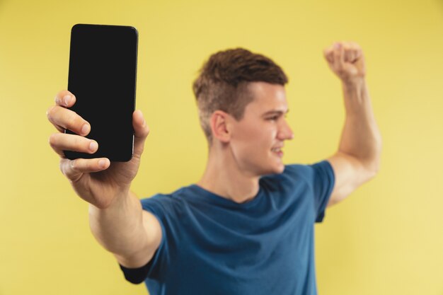 Retrato de medio cuerpo del joven caucásico en estudio amarillo