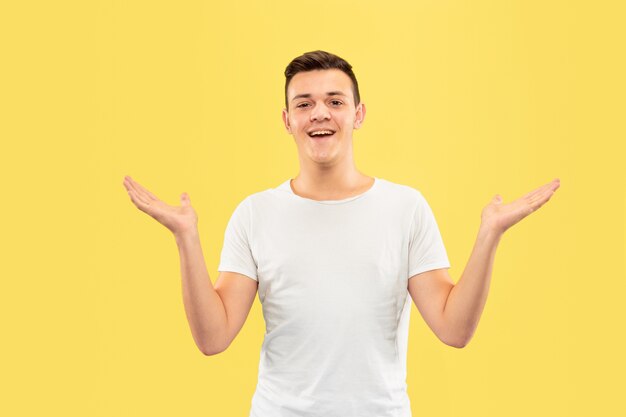 Retrato de medio cuerpo del joven caucásico en estudio amarillo