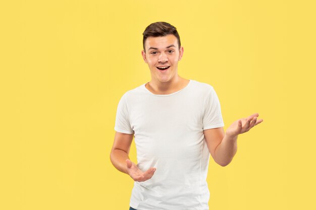 Retrato de medio cuerpo del joven caucásico en estudio amarillo