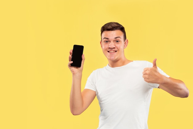 Retrato de medio cuerpo del joven caucásico en estudio amarillo