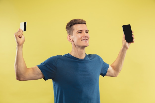 Retrato de medio cuerpo del joven caucásico en estudio amarillo