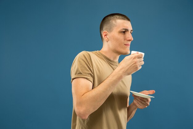 Retrato de medio cuerpo del joven caucásico en estudio azul