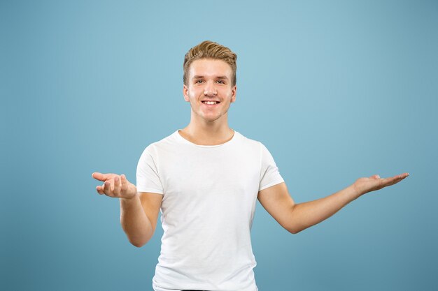 Retrato de medio cuerpo del joven caucásico en estudio azul