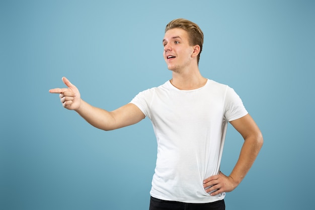 Retrato de medio cuerpo del joven caucásico en estudio azul