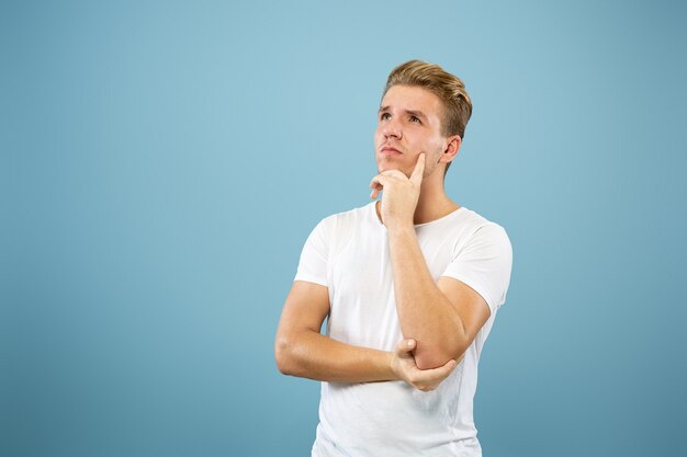 Retrato de medio cuerpo del joven caucásico en estudio azul