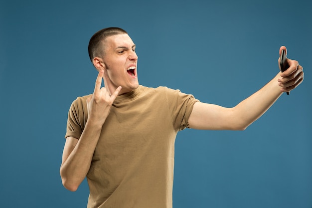 Retrato de medio cuerpo del joven caucásico en estudio azul