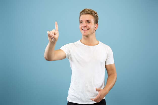 Retrato de medio cuerpo del joven caucásico en estudio azul