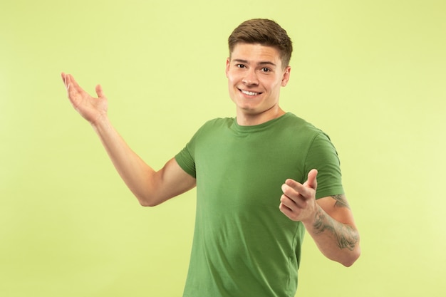 Retrato de medio cuerpo del joven caucásico en estudio verde