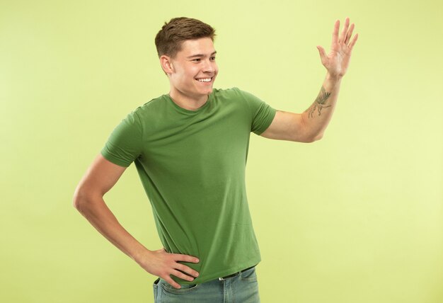 Retrato de medio cuerpo del joven caucásico en estudio verde