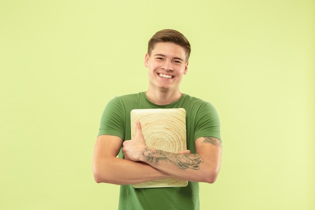 Retrato de medio cuerpo del joven caucásico en estudio verde