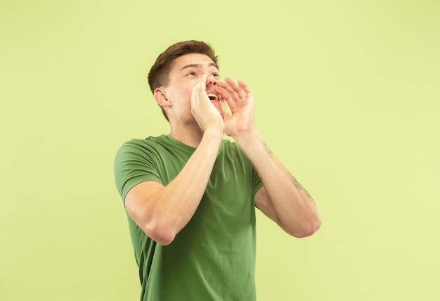 Retrato de medio cuerpo del joven caucásico en estudio verde