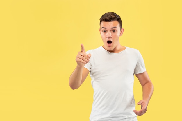 Retrato de medio cuerpo del joven caucásico sobre fondo amarillo de estudio. Hermoso modelo masculino en camisa. Concepto de emociones humanas, expresión facial, ventas, publicidad. Tocando una barra de búsqueda vacía.