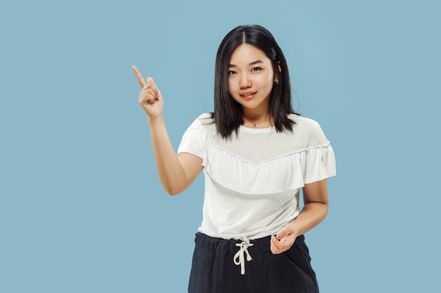 Retrato de medio cuerpo de la joven coreana sobre fondo azul.